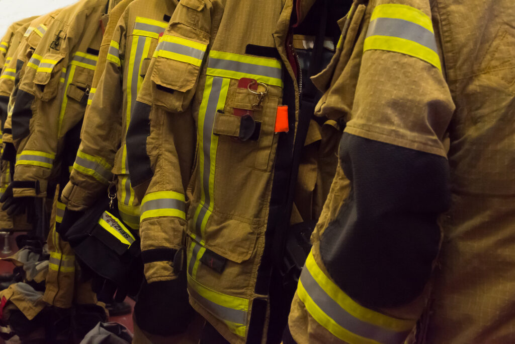 Vestimentas de proteção FR com faixas refletivas penduradas em ambiente operacional, representando EPI térmico desenvolvido para proteger trabalhadores contra chama repentina, arco elétrico e calor por radiação.