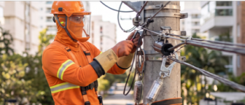 Eletricista com vestimenta de proteção contra arco elétrico em poste de energia