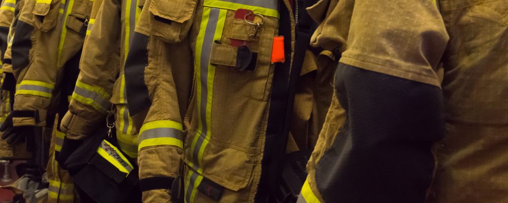 Vestimentas de proteção FR com faixas refletivas penduradas em ambiente operacional, representando EPI térmico desenvolvido para proteger trabalhadores contra chama repentina, arco elétrico e calor por radiação.